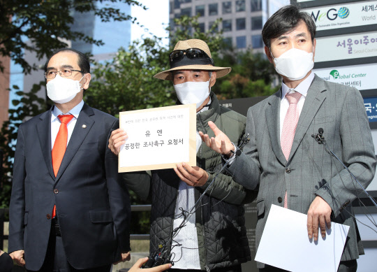 북한 피격 사망 공무원 A씨의 형 이래진(가운데)씨가 6일 서울 종로구 유엔 북한인권사무소를 방문해 전달할 공정한 조사 촉구 요청서를 들고 있다.   연합뉴스